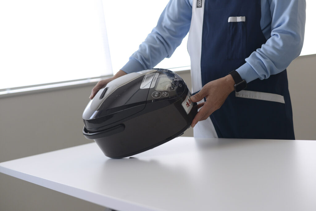 Staff inspecting a rice cooker for scratches.